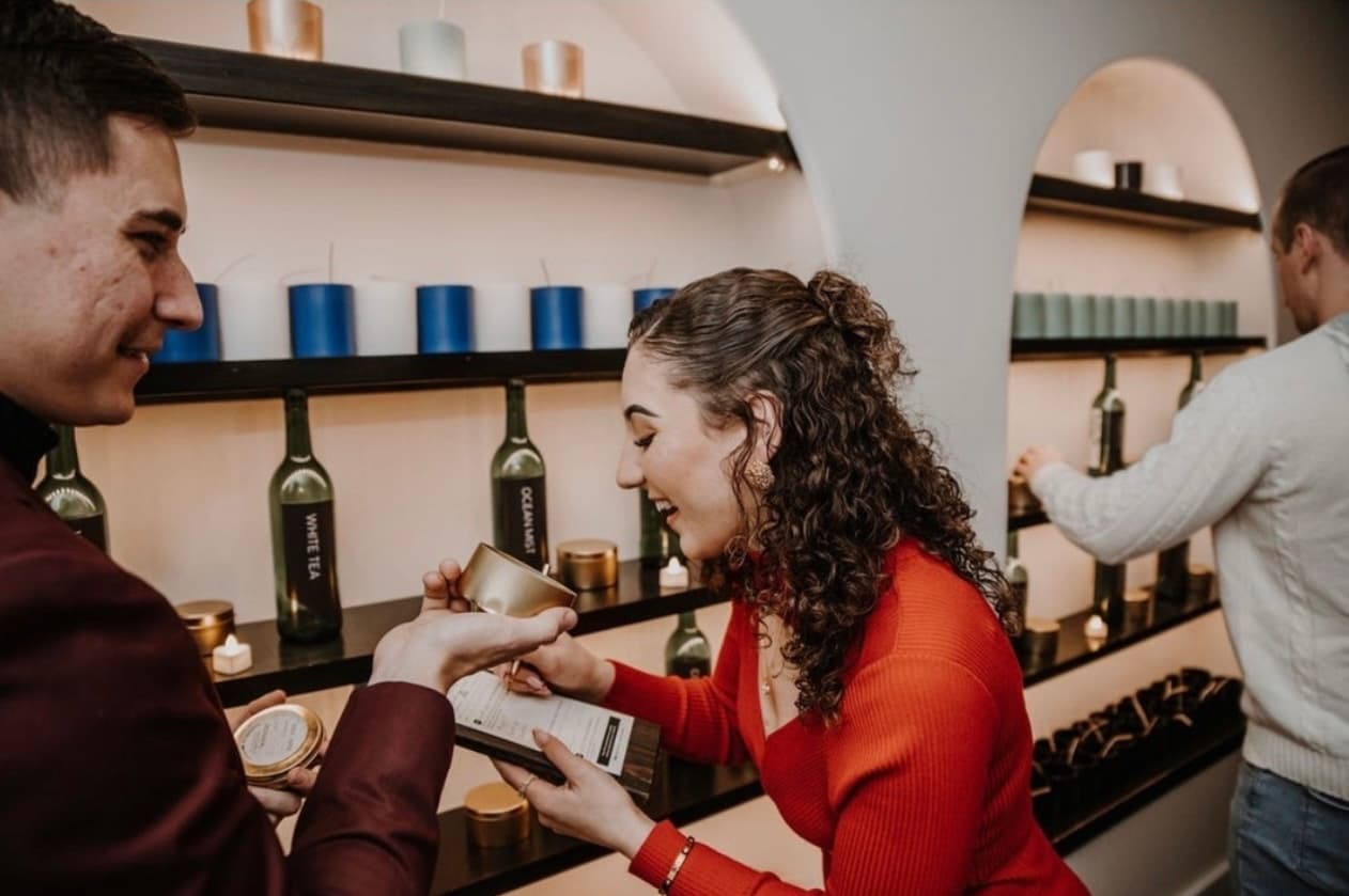 Two guests sharing a moment of joy while scent-testing at the Wax + Wine candle bar