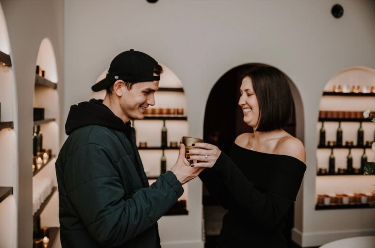 A couple laughing while holding a custom candle at Wax + Wine