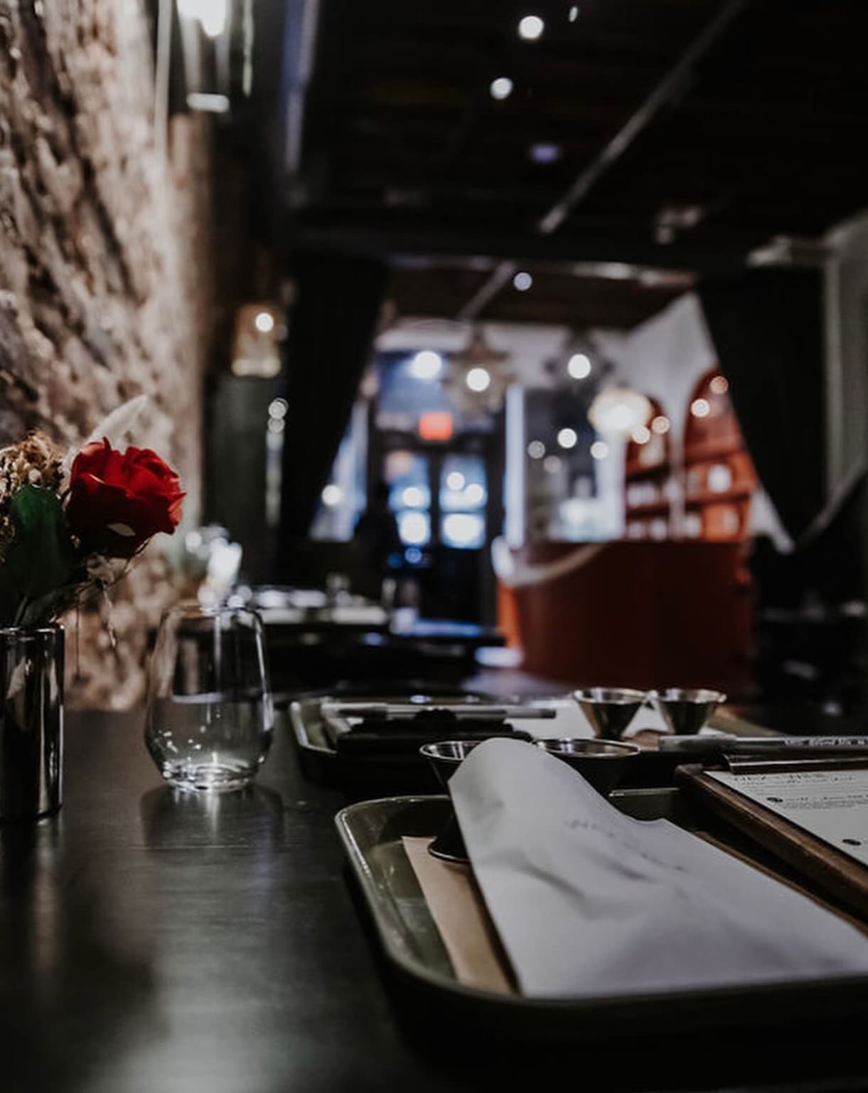 A single rose on the bar at Wax + Wine with the venue softly lit in the background