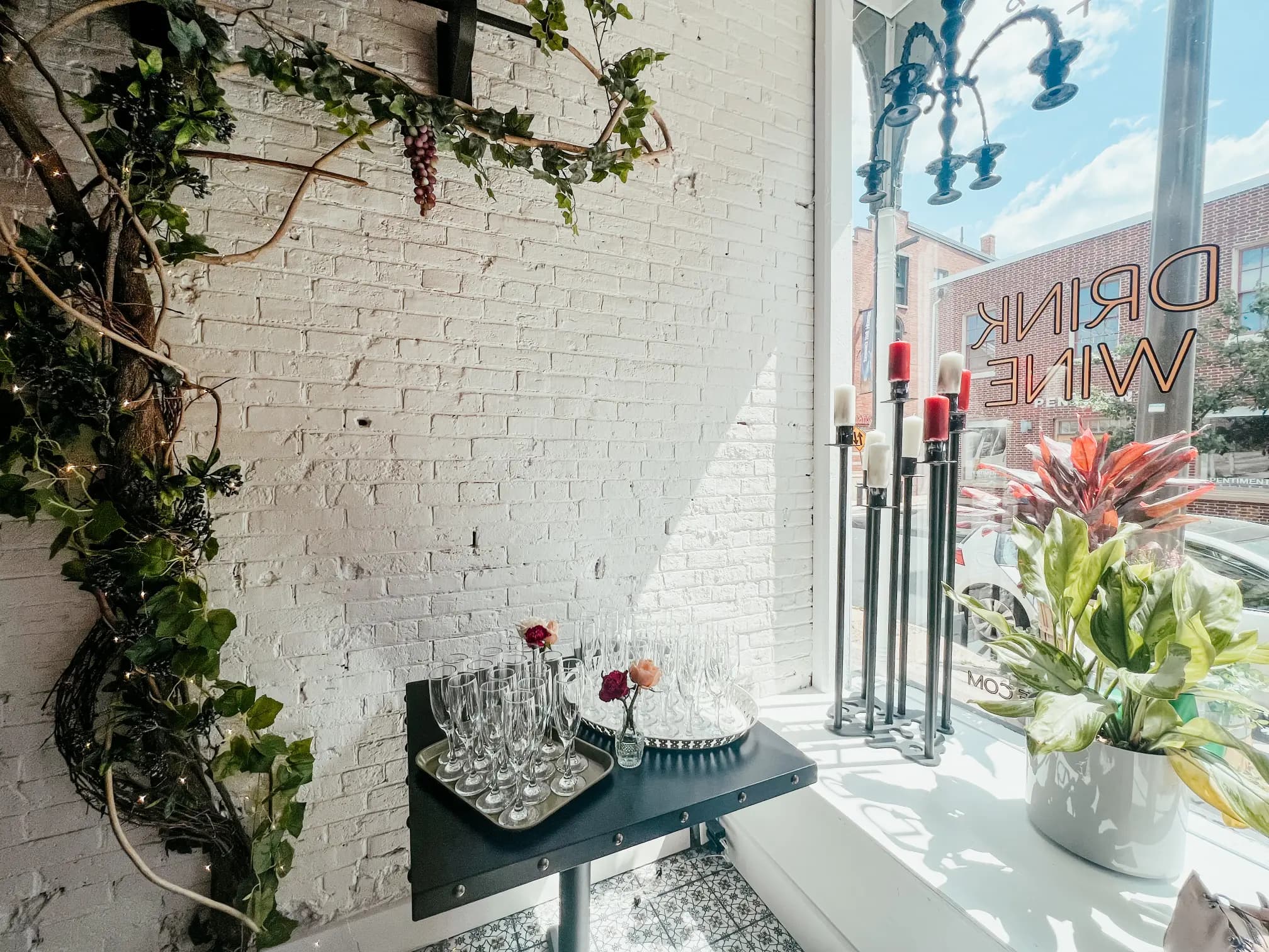Wax + Wine venue interior with brick walls, greenery, and wine glasses
