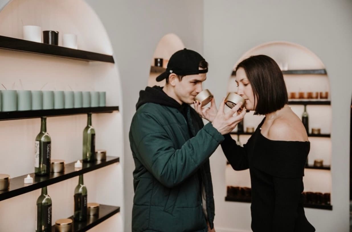A couple sharing a candle-smelling moment at the Wax + Wine Scent Cellar