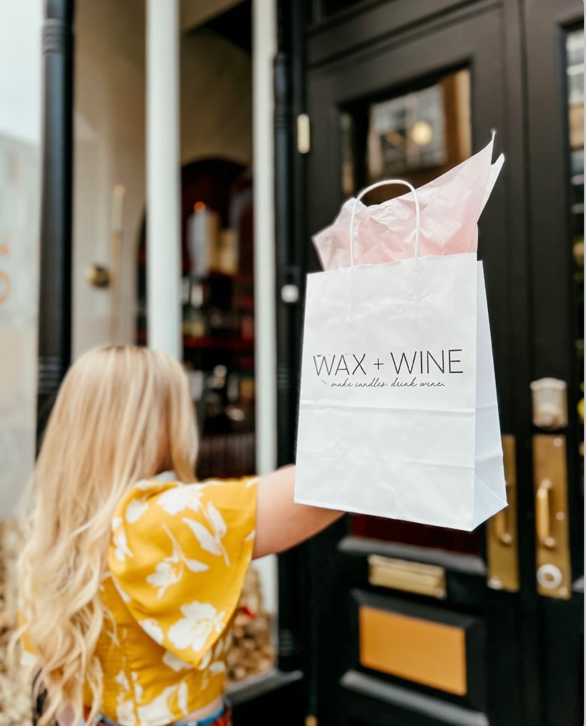 A guest leaving Wax + Wine carrying her custom candles in a Wax + Wine bag